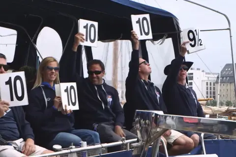 Judges hold up scorecards showing "10" and "9 1/2", indicating high diving scores.
