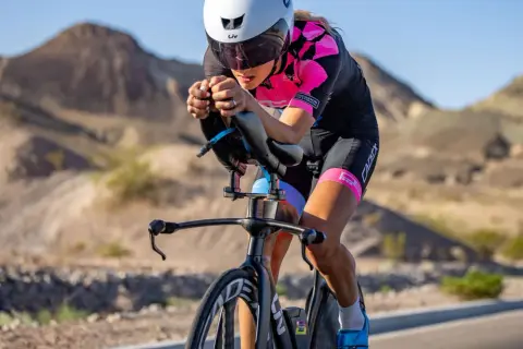 A determined woman competes in a womens triathlon, cycling intensely through a desert landscape.