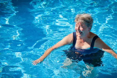 Smiling woman enjoys a refreshing swim, proving you can swim with a pacemaker and live life to the fullest.