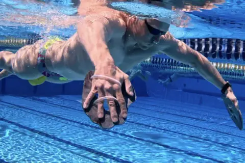 Swimmer performing a paddle drill, using hand paddles to increase resistance and build strength in the water.