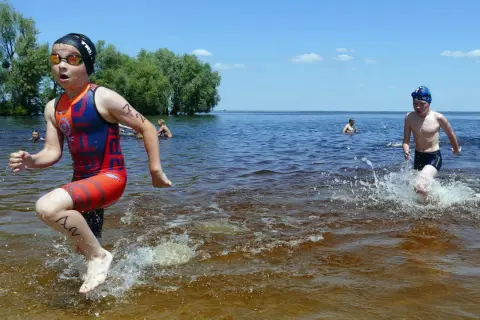 Young athletes splash through the water during a youth triathlon.