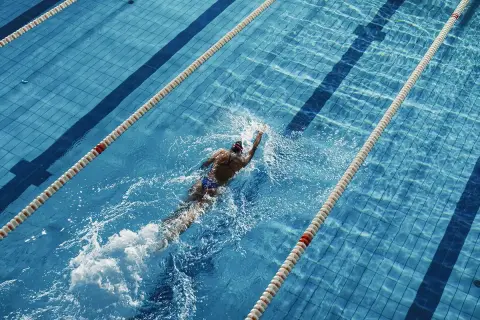 Swimmer powering through a lane, a great way to see how many calories do you burn in the pool.