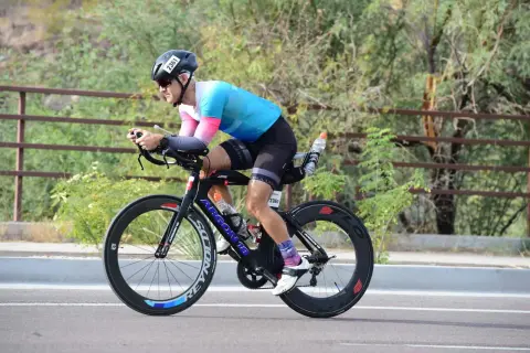 Athlete in aerodynamic position on a triathlon bike, training for a race.