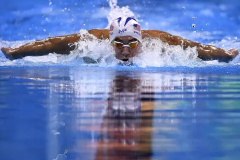 Swimmer Michael Phelps powers through the water, a blur of motion and spray. He's a master of the butterfly stroke, a style that revolutionized swimming, though who invented the butterfly stroke is debated.
