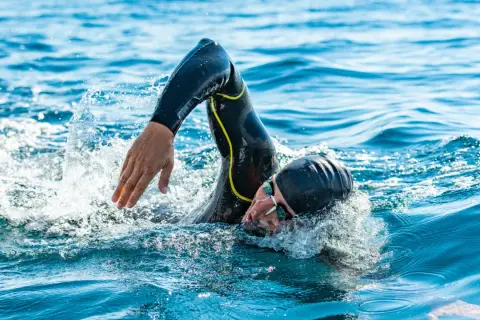 Athlete in wetsuit swims powerfully, a testament to the journey from couch to triathlon.