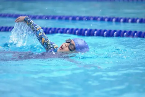 A young swimmer practices the side stroke, their arm slicing through the water.