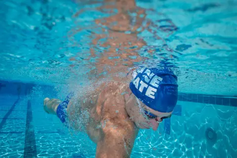 Underwater view of a swimmer's powerful swimmer lats as they glide through the blue water, bubbles trailing behind.