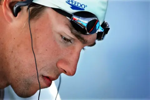 Michael Phelps in deep visualization, wearing Speedo cap and goggles, preparing for a race.