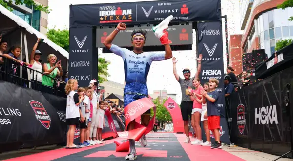 A triumphant athlete breaks the tape at the Memorial Hermann Ironman Texas, celebrating a victory in this demanding team triathlon event.