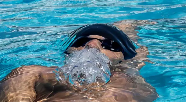 A swimmer exhales bubbles, showing that you can swim with a scraped knee.