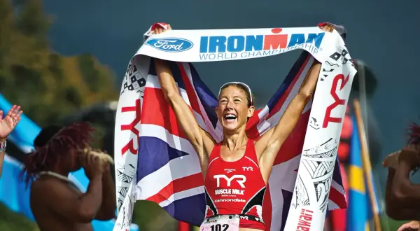 Chrissie Wellington celebrates her Ironman World Championship win, draped in the Union Jack and holding the Ford Ironman banner.