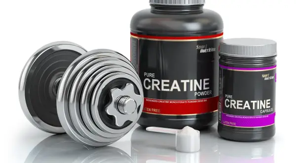 Dumbbells and containers of creatine powder and capsules, ideal for swimmers looking to boost their performance.