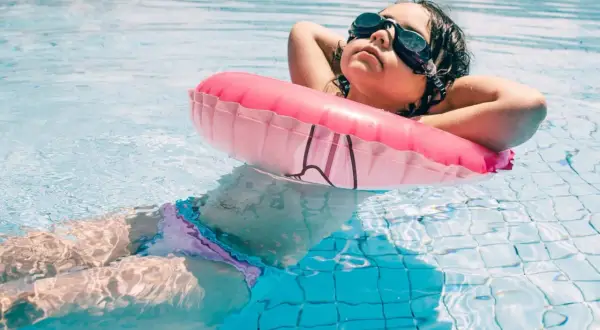 A child relaxes in a pool with a pink float, enjoying a moment of peace after swim lessons for 1 year old.