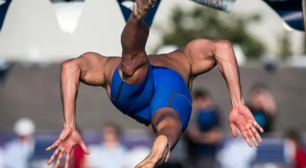A swimmer in mid-air, showcasing the powerful back muscles developed through dedicated back exercises.