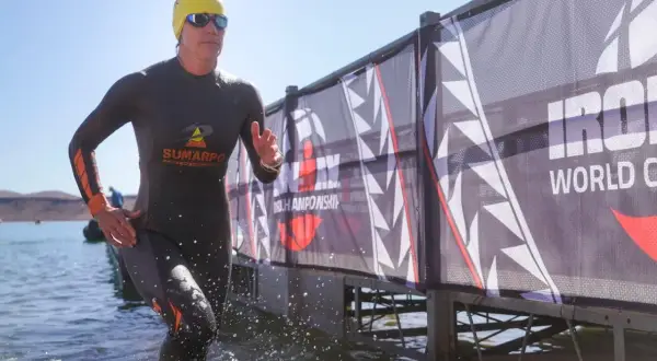 Athlete emerges from water, ready for the full Ironman distance. A banner reads "Ironman World Championship.