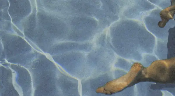 Sunlight dances on the water's surface, illuminating submerged feet. Does chlorine kill yeast on skin? This pool might offer an answer.