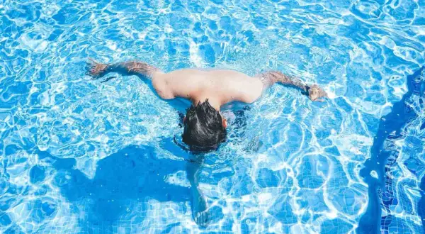 A person swims in a bright blue pool. Wondering how often should I swim? This refreshing activity is great for fitness.