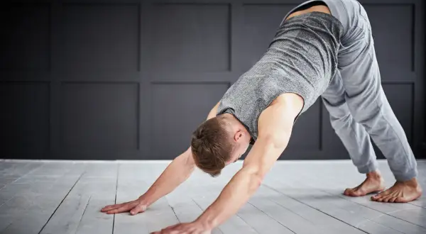 Man in downward-facing dog pose, a key stretch for yoga for triathletes, improving flexibility and recovery.
