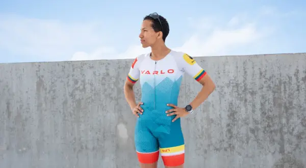 A woman in a vibrant blue and white triathlon suit, ready for competition. This is what to wear for a triathlon.