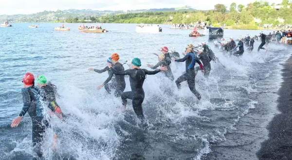 Triathletes charge into the water, kicking up spray as they begin the swim portion of a boulder half ironman race.