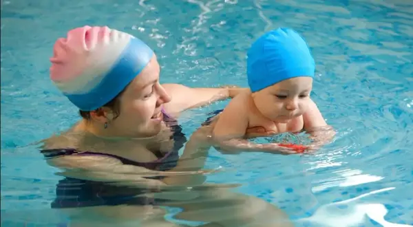 A mother and baby in a pool. It's never too early to consider when to start baby swim lessons for water safety and fun.