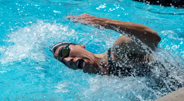 Swimmer in goggles and cap powers through the water, mid-stroke, preparing for a flip turn.