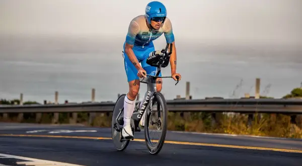 A determined triathlete, perhaps a beginner, races on a bike, focused on the road ahead.