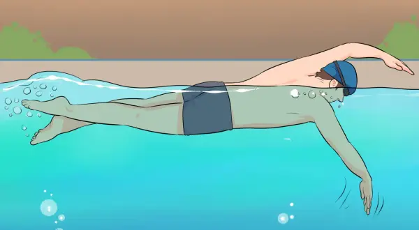 A person in swim cap and goggles practices freestyle swimming, a common stroke for beginner swim lessons for adults.