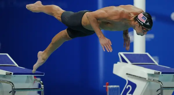 Michael Phelps dives into the water, his body streamlined. His focused expression hints at the intense effort and controlled michael phelps heart rate required for peak performance.