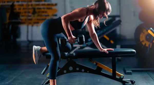 Woman performing a dumbbell row as part of her triathlon strength training plan.