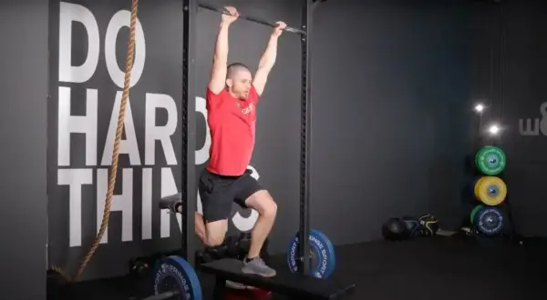 Man performing a hanging exercise, possibly part of butterfly sets, in a gym.