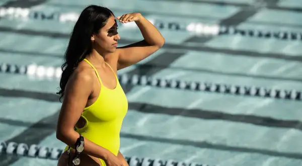 A determined lap swimmer shields her eyes, ready to dive into the pool.