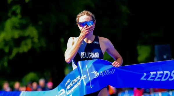 Cassandre Beaugrand, with hand over mouth, crosses the finish line at the World Triathlon Championship in Leeds, a moment of triumph and emotion.