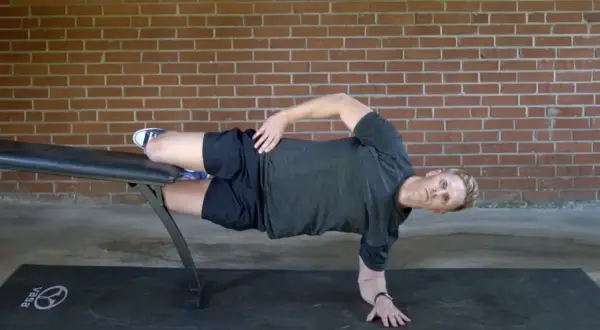 Man performing a side plank on a bench, a key exercise for core workouts for swimmers.