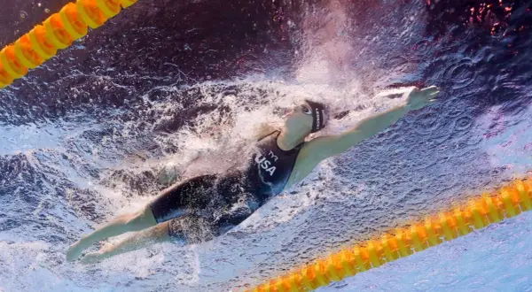 Katie Ledecky training underwater, powering through the water in a USA swimsuit.
