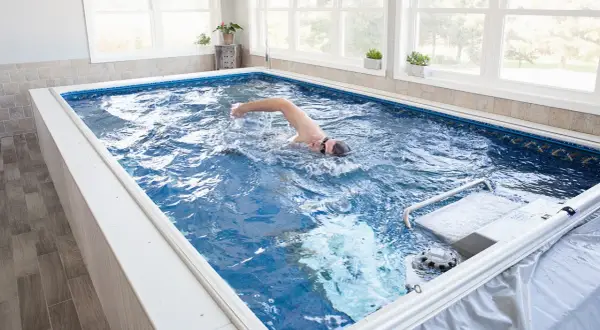 Man swims laps in a compact triathlon pool, enjoying an endless swim against a gentle current.