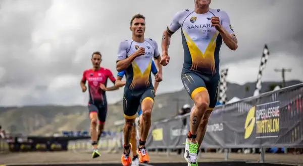 Triathletes race, pushing their limits. The lead runner's determined face hints at the grueling Ironman triathlon distances ahead.