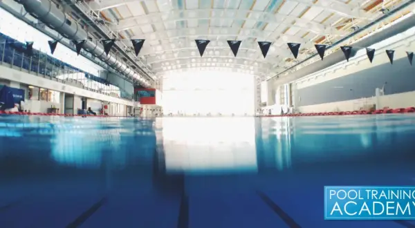 An empty indoor swimming pool with black Speedo flags. While chlorine kills many germs, does chlorine kill COVID?