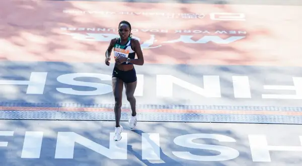 Runner crosses the finish line in her Under Armour tri suit, a testament to her endurance and dedication.
