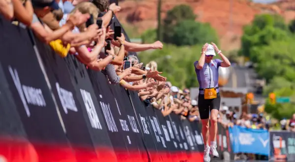 Athlete 53 runs towards the finish line at Ironman 70.3 St. George, greeted by a cheering crowd.