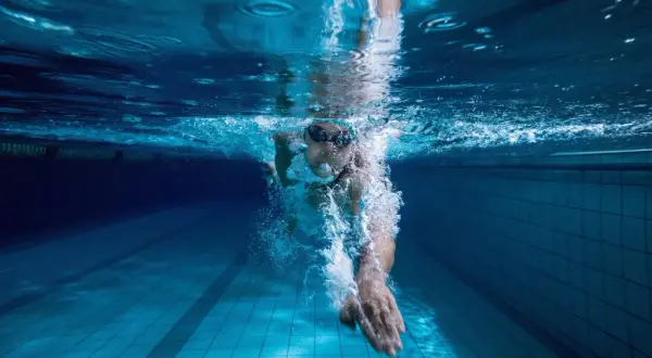 Underwater view of a swimmer pushing through the water, a powerful stroke for endurance swim workouts.