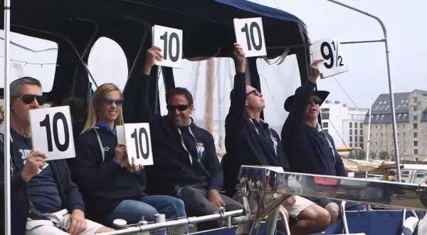 Judges hold up scorecards showing "10" and "9 1/2", indicating high diving scores.