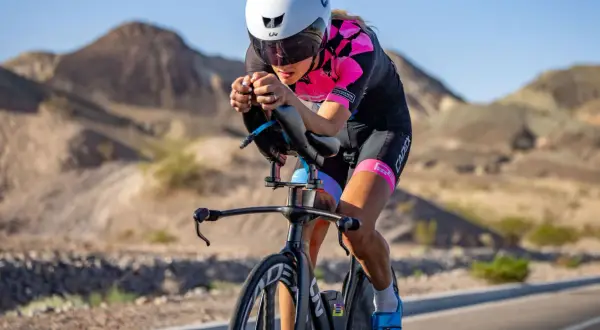 A determined woman competes in a womens triathlon, cycling intensely through a desert landscape.