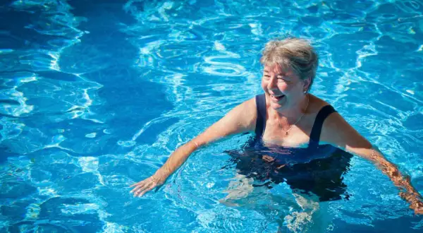 Smiling woman enjoys a refreshing swim, proving you can swim with a pacemaker and live life to the fullest.