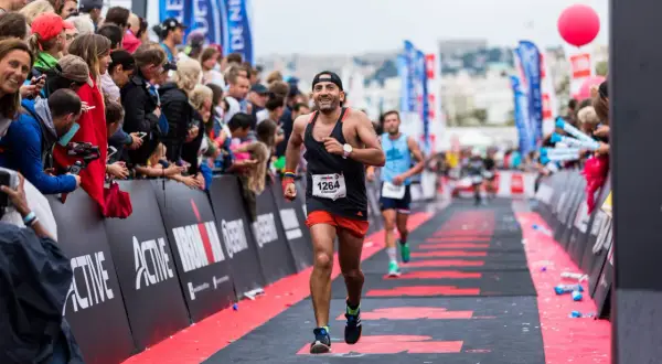A determined runner approaches the Ironman finish line, cheered on by a crowd.
