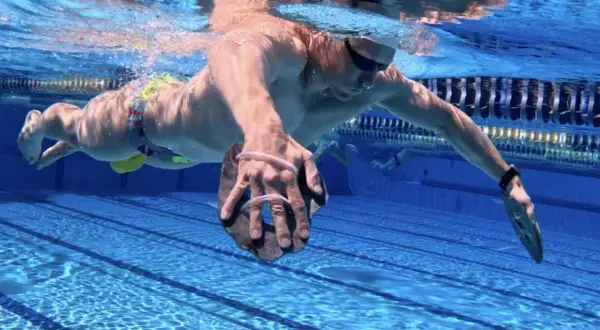 Swimmer performing a paddle drill, using hand paddles to increase resistance and build strength in the water.