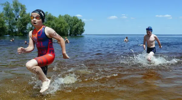 Young athletes splash through the water during a youth triathlon.