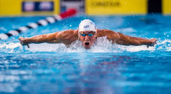Michael Phelps powers through the water, his arms extended in a butterfly stroke, as if he could fly.