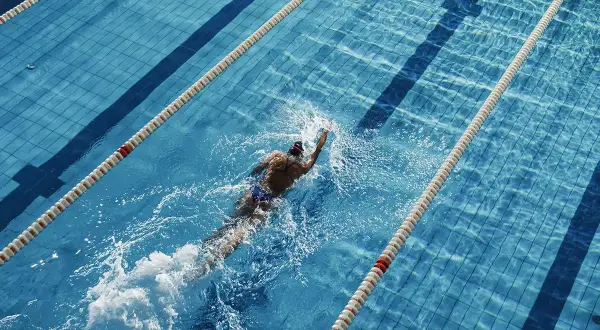 Swimmer powering through a lane, a great way to see how many calories do you burn in the pool.