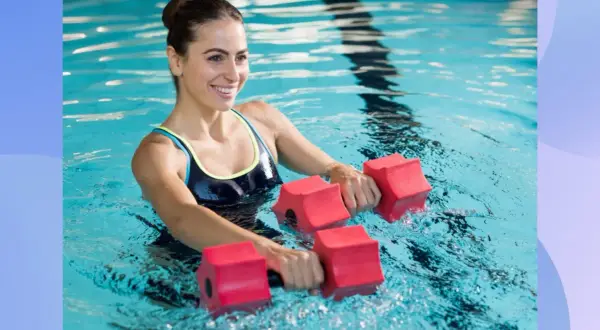 Woman smiling while doing pool exercises for abs with red water dumbbells.